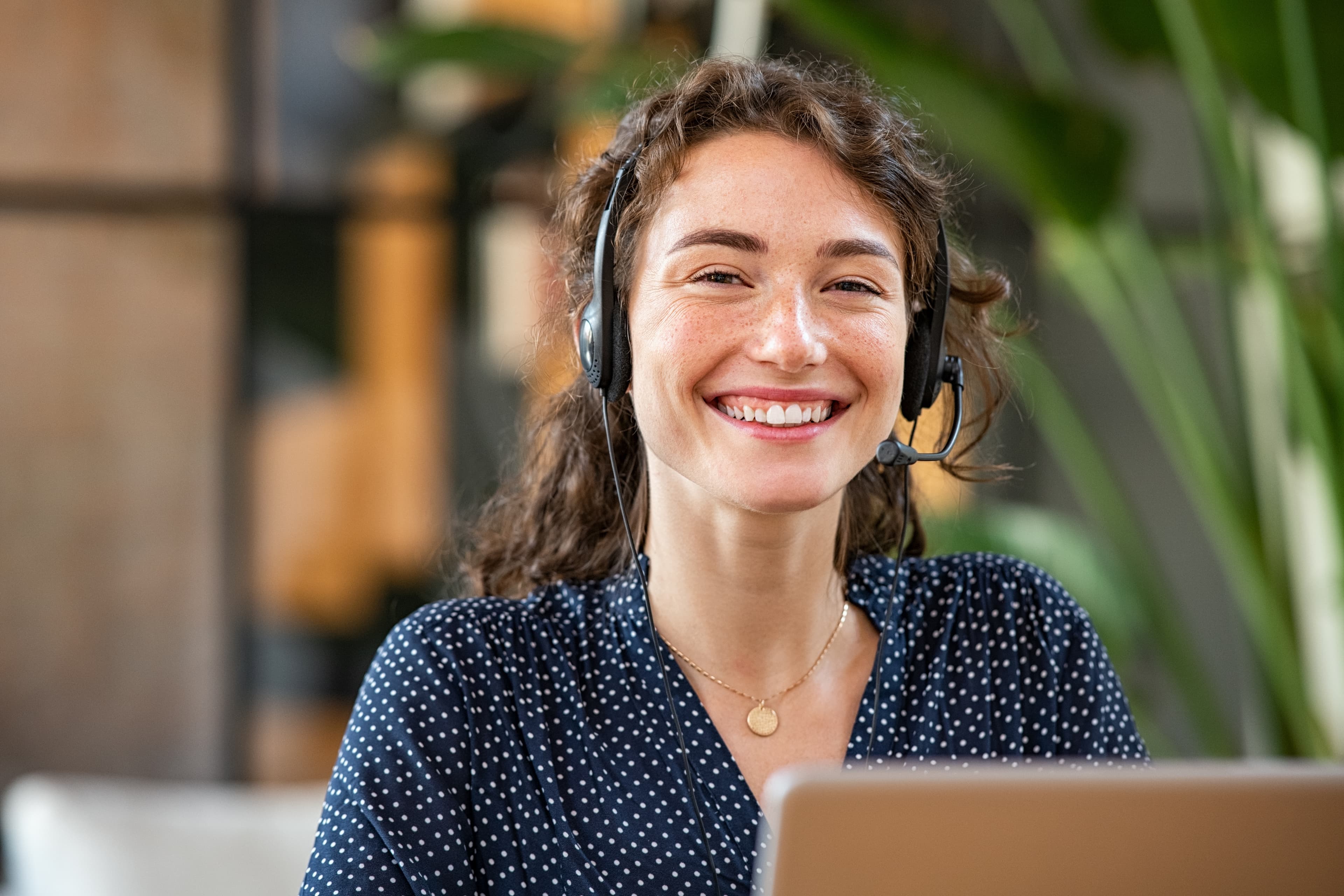 Junge Telefon-Service Mitarbeiterinn lächelt mit Headset in die Kamera