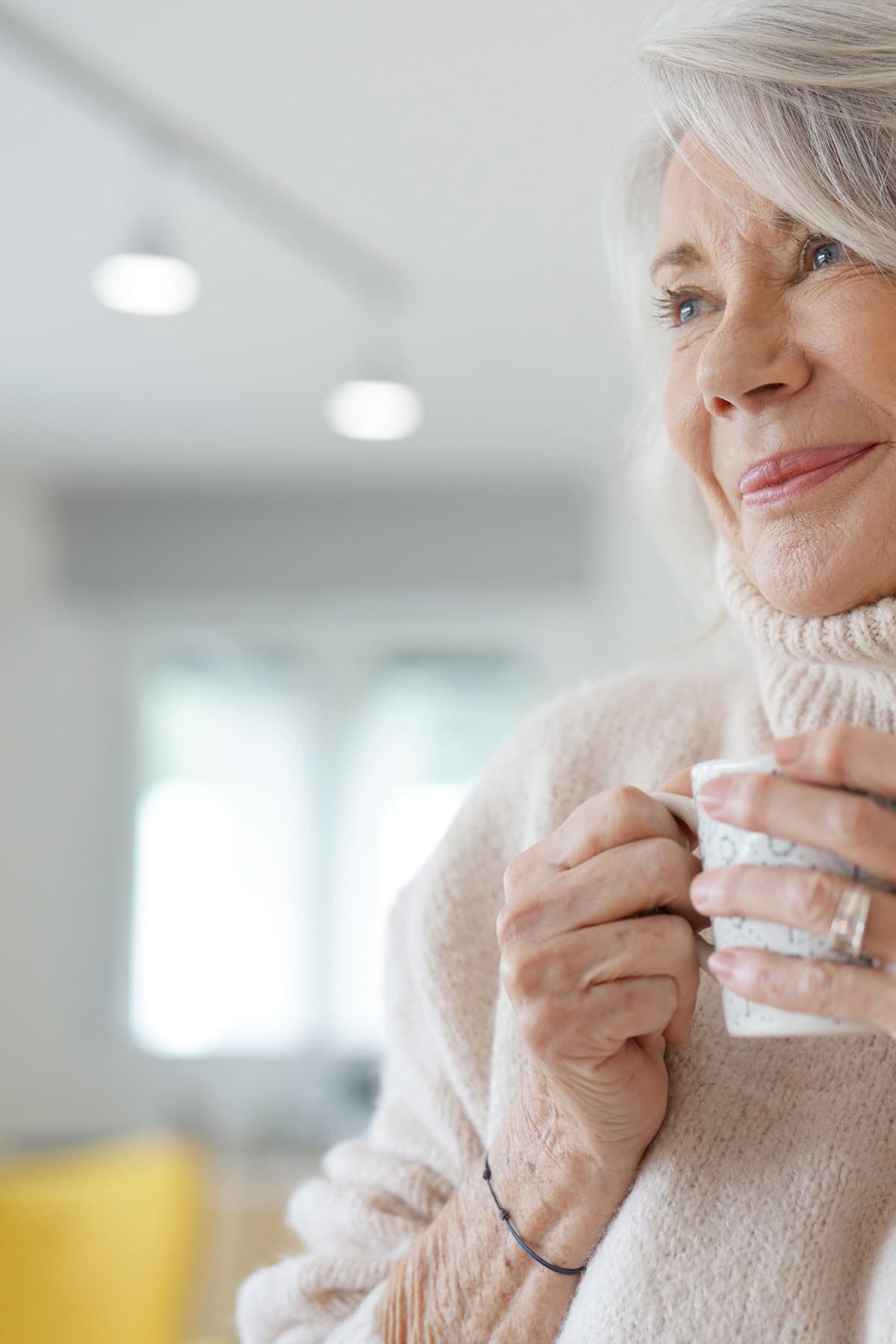 Ältere Dame genießt Ihren Kaffee un d grinst zufrieden.